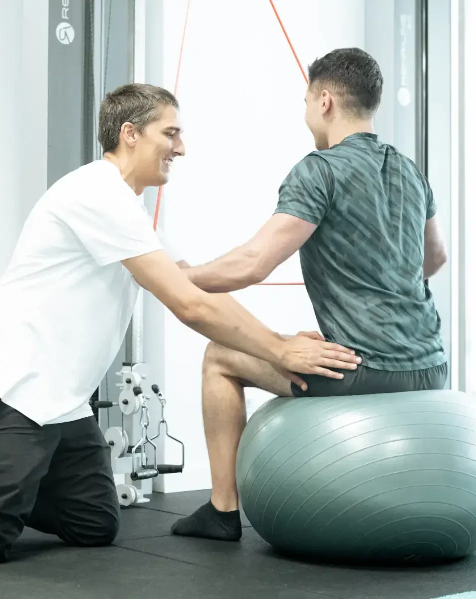 Therapeut unterstützt Patienten beim Stabilitäts-Training auf dem Gymnastikball in der neurologischen Physiotherapie in Karlsruhe