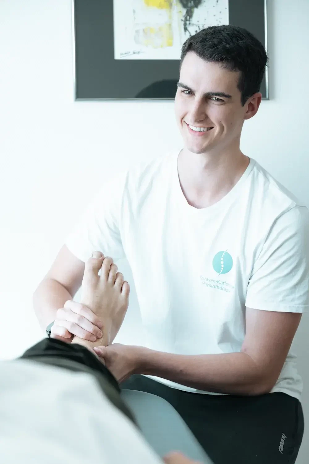 Physiotherapeut führt orthopädische Physiotherapie in Karlsruhe durch und behandelt den Fuß eines Patienten in der Praxis